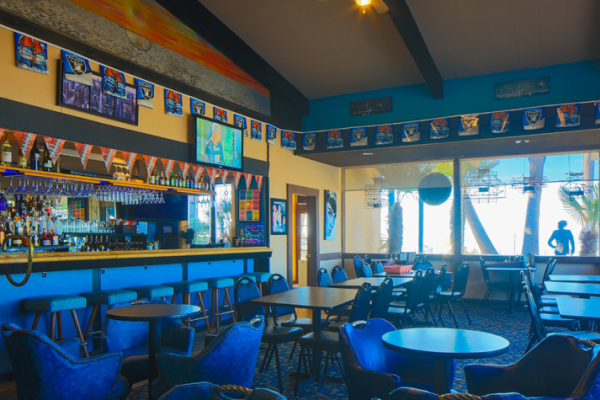 tables and chairs inside bar with televisions playing sports